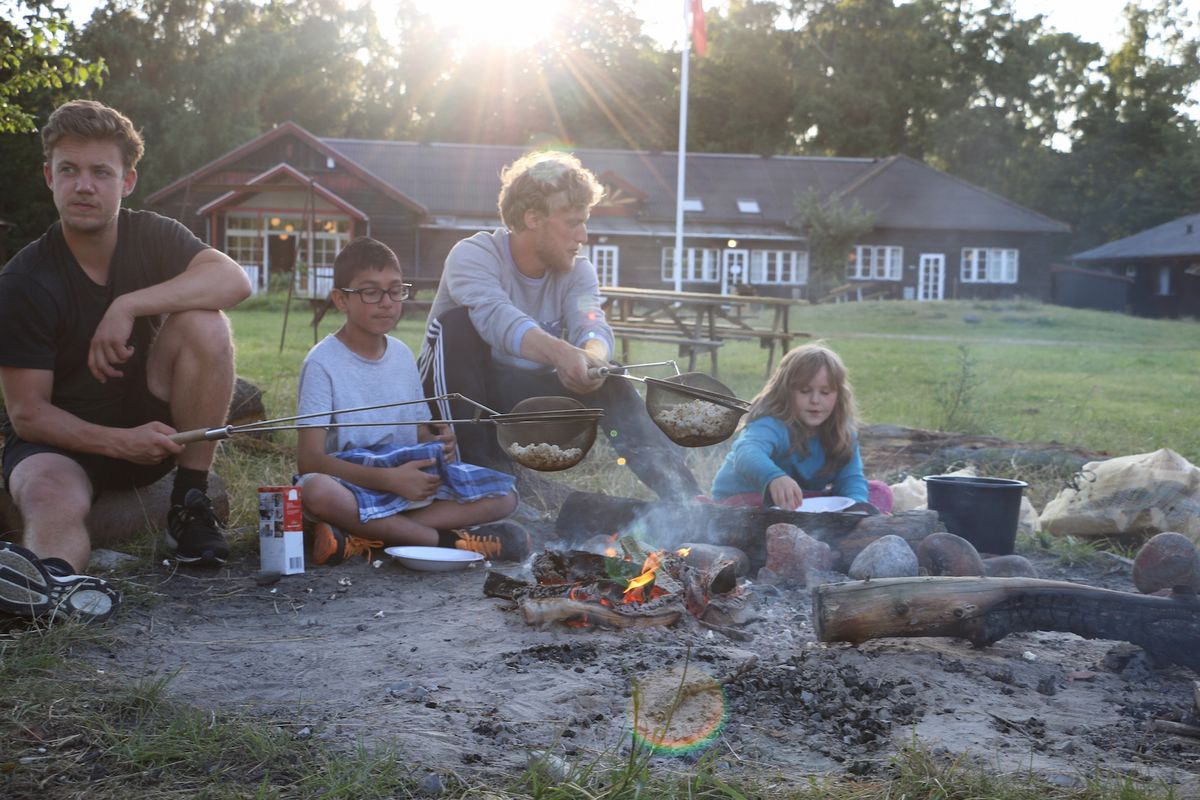 Den sidste aften blev der poppet popcorn over bålet, som med stor fairness blev fordelt blandt de 18 børn af Bobby, som sidder mellem de to voksne og vogter over skålen med de færdigpoppede godter. Foto: Jennifer Jensen Den sidste aften blev der poppet popcorn over bålet, som med stor fairness blev fordelt blandt de 18 børn af Bobby, som sidder mellem de to voksne og vogter over skålen med de færdigpoppede godter. Foto: Jennifer Jensen